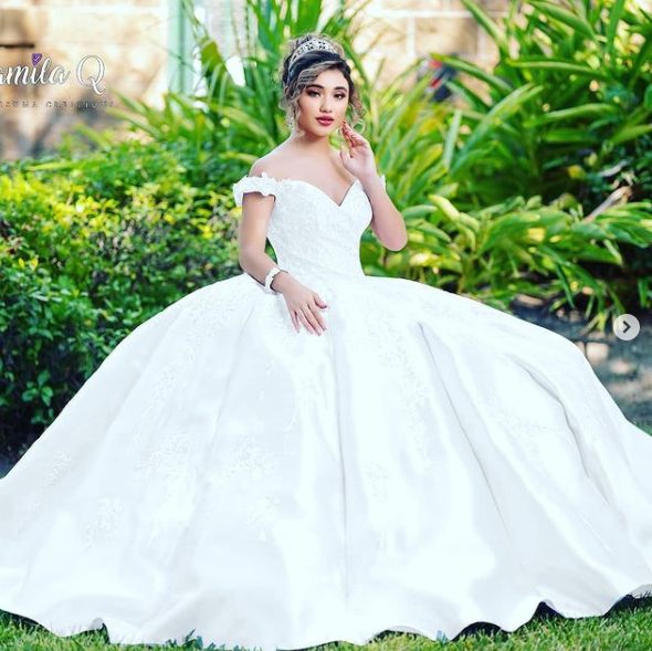 A woman in a Quinceanera gown dress posing for a picture