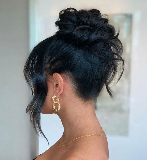 A woman with long black hair wearing gold hoop earrings