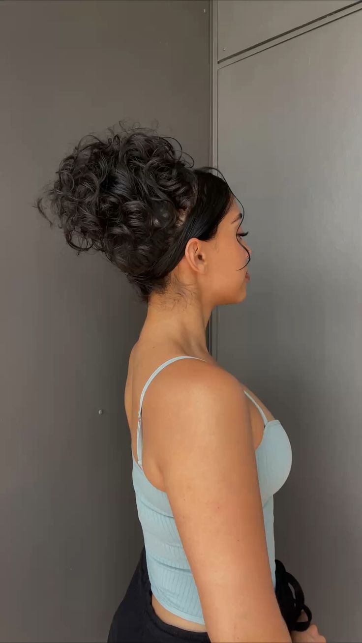 A woman with black hair standing in front of a gray wall