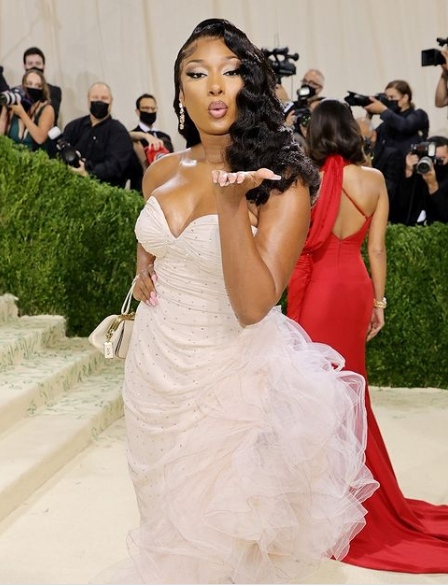 A woman in a white dress standing on a red carpet at the Quinceanera gown 2021 Met Gala.