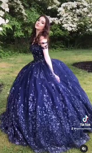 A woman in a blue Quinceanera gown standing in a field.
